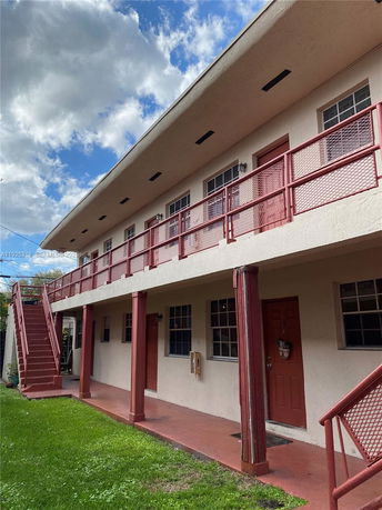 Front view of a two-story building with an outdoor staircase and red railings.