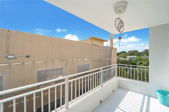 Balcony view overlooking a neighboring building and some trees.