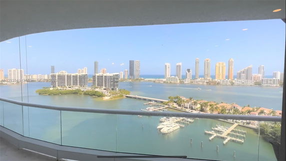 Panoramic view from a building showing water, boats, and distant city skyline.
