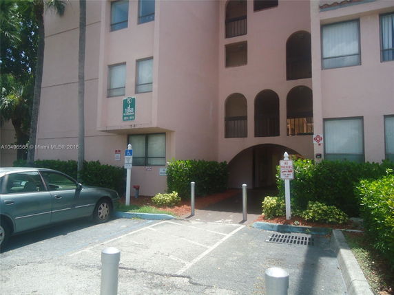 Parking area in front of a multi-story building entrance.