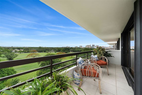 Panoramic view from a balcony overlooking green fields and distant cityscape.