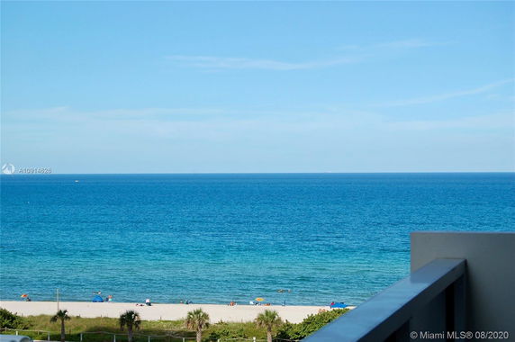 Panoramic view of the ocean from a building, with a beach visible in the foreground.