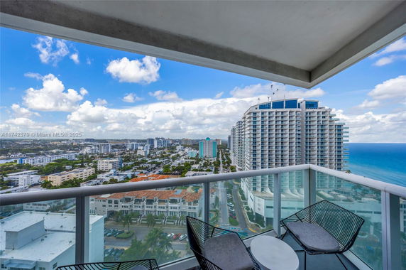 Panoramic view from a balcony overlooking city buildings and ocean.