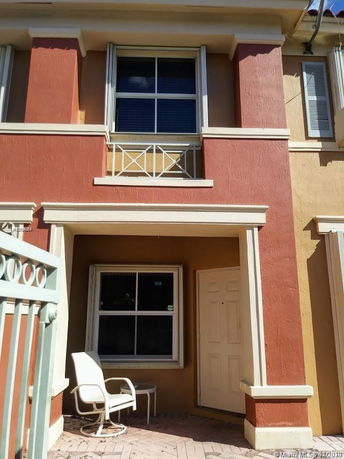 Front view of a two-story house with two windows and an entrance door.