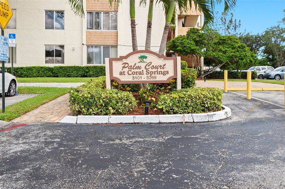 Front view of a multi-story building with Palm Court at Coral Springs signage.