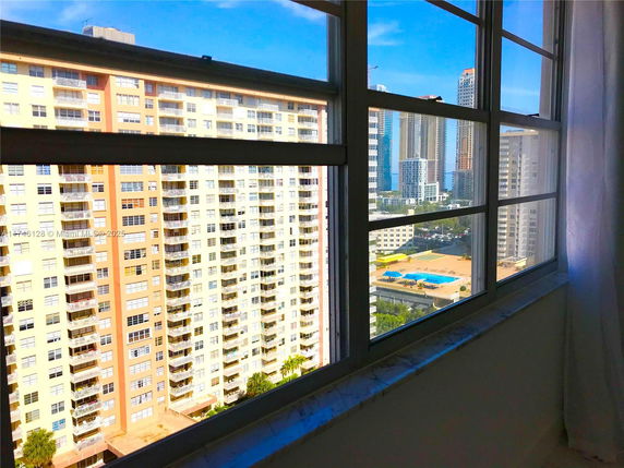 View from a window showing high-rise buildings and a distant swimming pool.