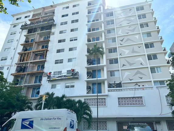 Front view of a multi-story building with a facade being renovated.