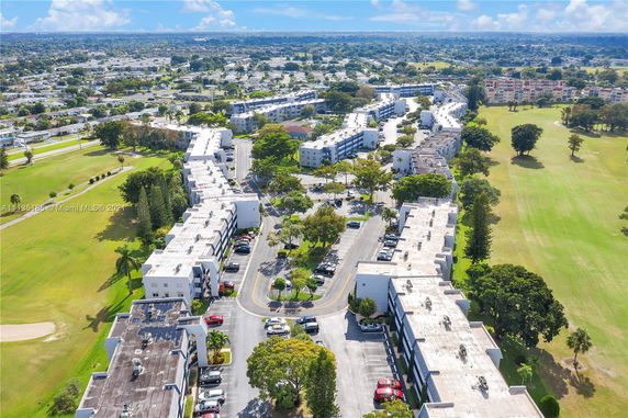 Panoramic view of a residential complex with multiple buildings and parking areas, surrounded by greenery.