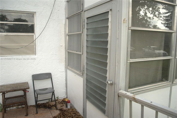 Exterior corner view of a building with white stucco walls and glass windows.