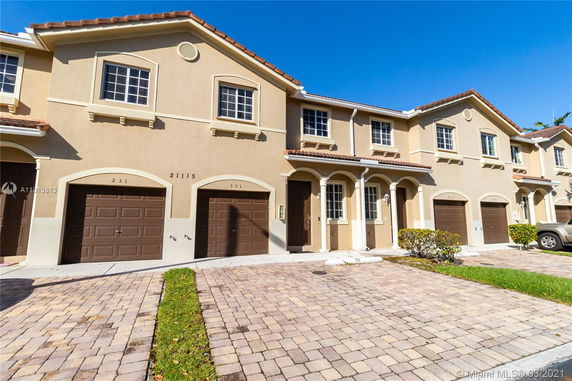 Front view of a two-story townhouse with a garage and arched entryway.