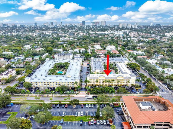 Aerial view of multiple apartment buildings in a residential area with nearby parking lots and city skyline in the background.