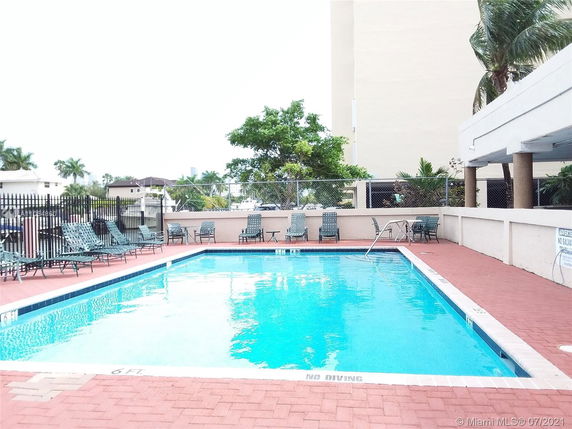Outdoor pool area with seating and surrounding buildings.