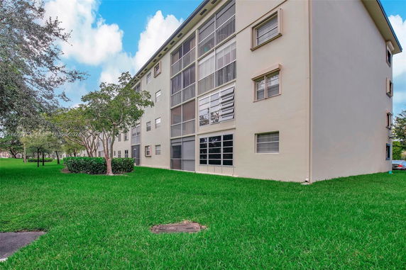 Side view of a multi-story residential building with screened balconies and beige exterior.