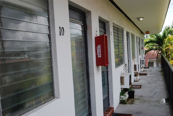 Exterior corridor of a multi-level building with numbered doors and a fire extinguisher case.