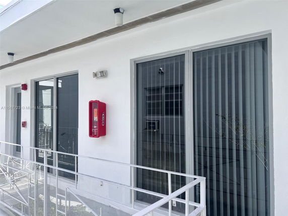 Exterior view of a building with large glass doors and a red fire extinguisher cabinet.