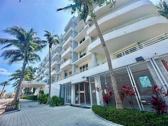Front view of a multi-story building with balconies and a walkway.