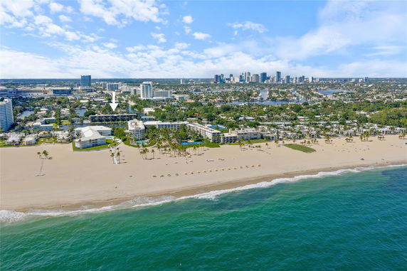 Panoramic view of beachfront buildings and distant city skyline.