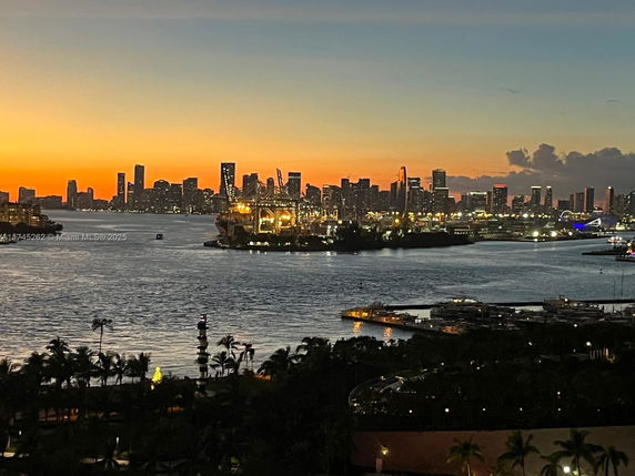 Panoramic view of a city skyline at sunset with water and docks in the foreground.