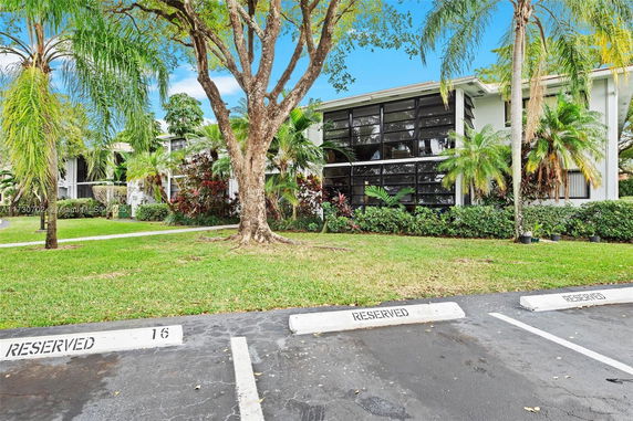 Front view of a two-story residential building with large windows and surrounding palm trees.