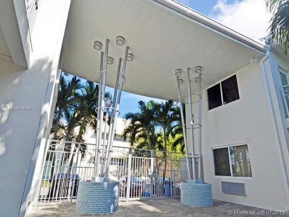 Front view of a modern building with artistic support columns and gated entrance.
