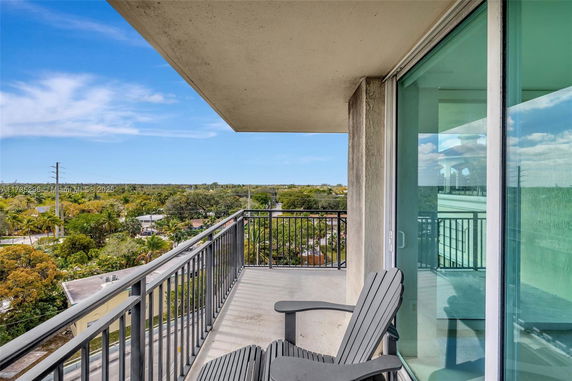Balcony view from a high-rise building overlooking lush green surroundings and distant horizon.