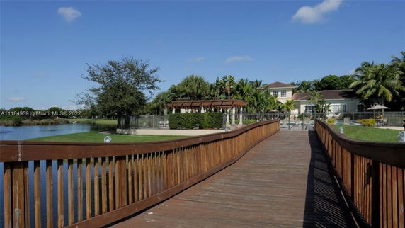 Wooden walkway leading to a house with a lake and trees in the background.