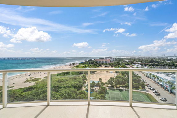Panoramic view from a balcony overlooking a beach and ocean.