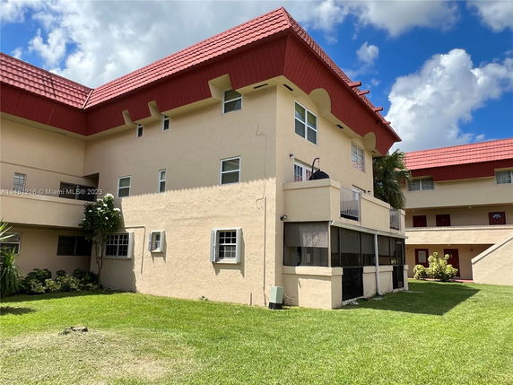 Front view of a multi-level building with red tiled roof and beige exterior.