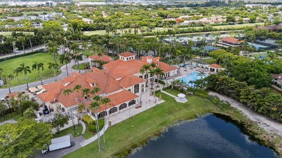 Aerial view of a large building with red tile roof, swimming pool, and surrounding greenery.