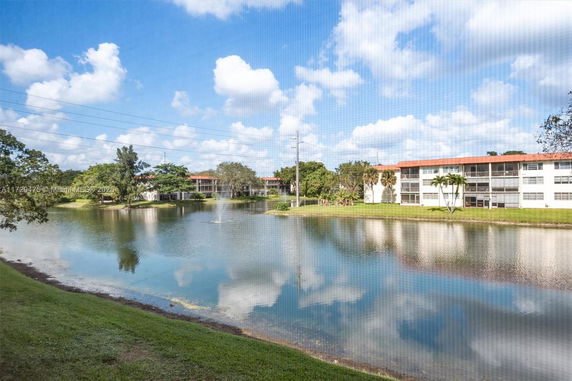 View of multiple residential buildings near a pond with a fountain.