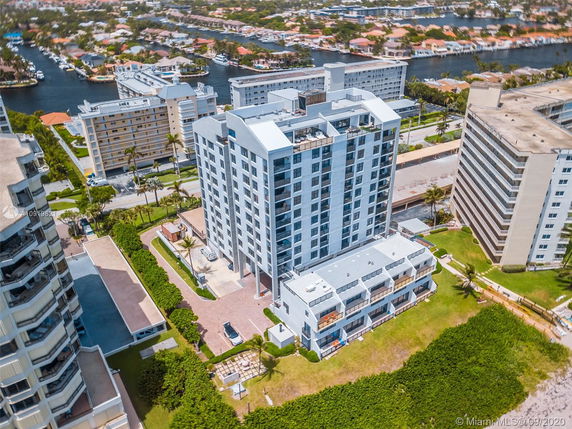 Aerial view of a multi-story residential building surrounded by other buildings and water channels.