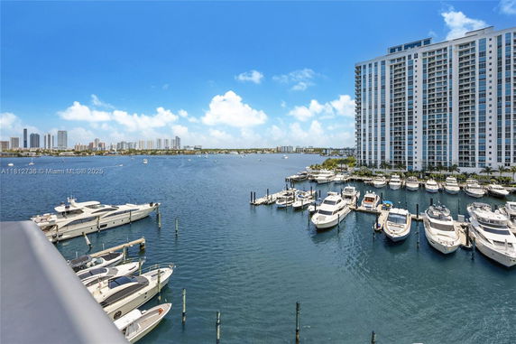 Panoramic view of a marina with boats and a high-rise building nearby.