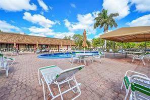Outdoor area with a swimming pool and sun loungers under a clear blue sky.