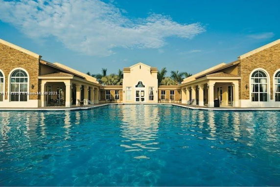 Large outdoor swimming pool adjacent to a building with arched windows.