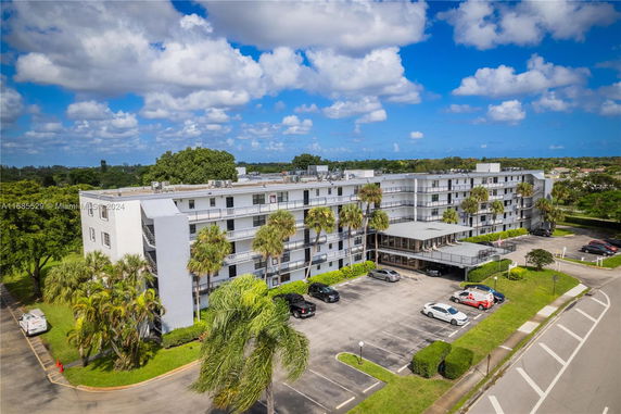 Front view of a multi-story residential building with balconies and parking area.