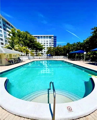 Outdoor swimming pool in front of a multi-story building.