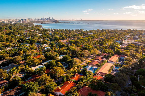 Aerial view showing a wide expanse of residential areas and water with a distant city skyline.