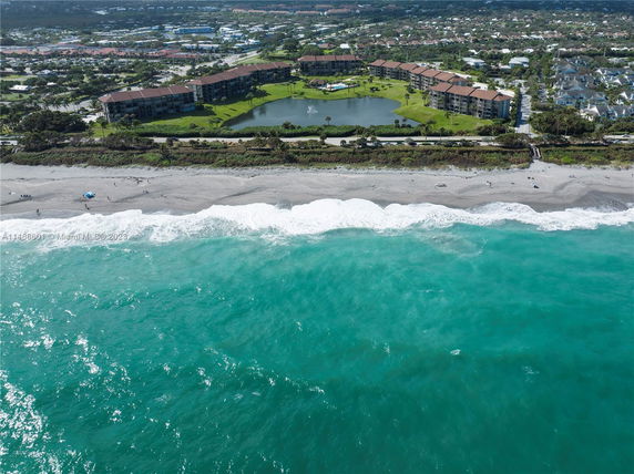 Aerial view of seaside residences with a beach and ocean in the foreground.