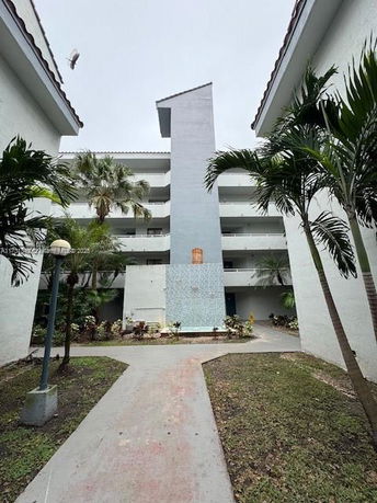 Front view of a multi-story building with white walls and exposed walkways.
