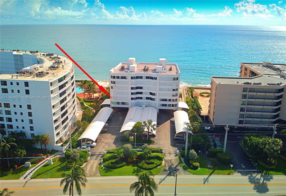 View of a group of oceanfront residential buildings with a focus on a central white multi-story structure.