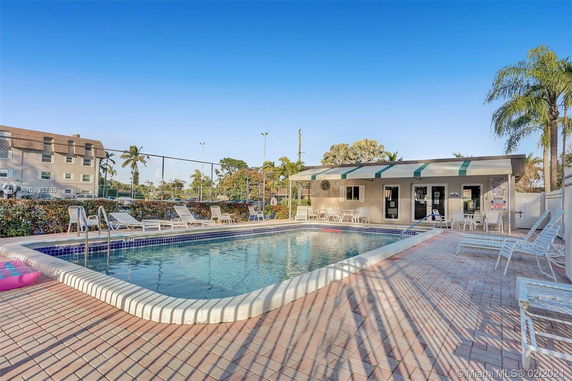 Outdoor swimming pool with lounge chairs and adjacent building.