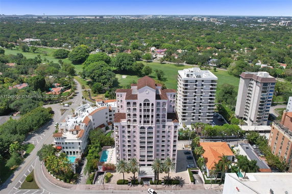 Aerial view of a multi-story residential building with a golf course and trees in the background.