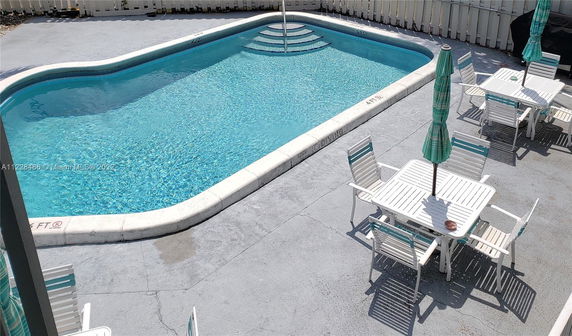 Outdoor swimming pool area with tables and chairs.