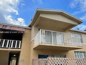 Front view of a two-story house with a balcony and beige exterior.
