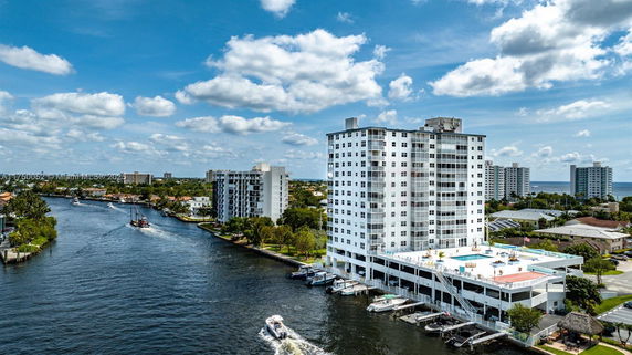 High-rise building with a rooftop pool, overlooking a waterway and surrounding cityscape.