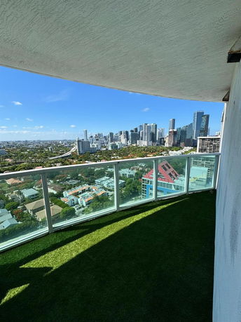 Panoramic cityscape view from a balcony with glass railing.