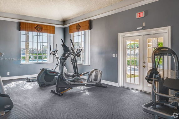 Indoor gym area with exercise equipment and windows.