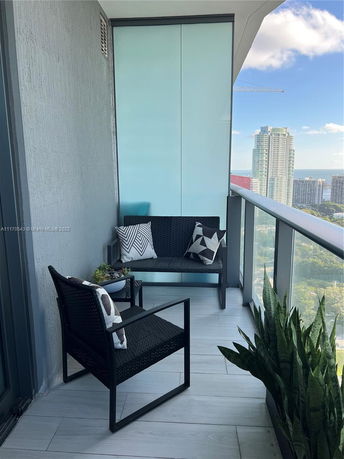 Balcony view from a high-rise building with outdoor furniture and cityscape in the background.