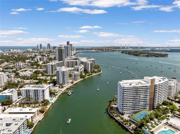 Panoramic view of a city skyline with tall buildings near a waterway and boats.
