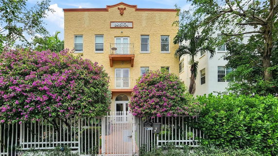 Front view of a multi-story building with a balcony and gated entrance.